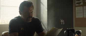 Movie still from “Only the Brave” (2017), directed by Joseph Kosinski – A man sitting at a table looking at papers; Close Up shot, Over the shoulder angle