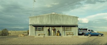 Movie still from “Only the Brave” (2017), directed by Joseph Kosinski – Three men are standing in front of a metal building; Extreme Wide shot, Low angle