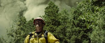 Movie still from “Only the Brave” (2017), directed by Joseph Kosinski – A man in a yellow jacket standing in front of trees; Medium shot, Low angle