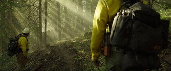 Movie still from “Only the Brave” (2017), directed by Joseph Kosinski – A man in a yellow jacket walking through the woods; Wide shot, Low angle