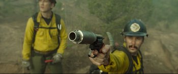 Movie still from “Only the Brave” (2017), directed by Joseph Kosinski – A man holding a gun in his hand while standing next to another man; Close Up shot, Over the shoulder angle