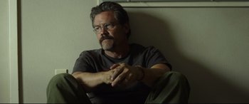 Movie still from “Only the Brave” (2017), directed by Joseph Kosinski – A man sitting on the ground with his hands crossed; Close Up shot, Low angle