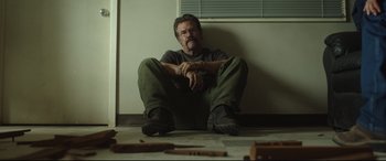 Movie still from “Only the Brave” (2017), directed by Joseph Kosinski – A man sitting on the floor in front of a window; Medium shot, Low angle