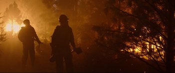 Movie still from “Only the Brave” (2017), directed by Joseph Kosinski – A person is standing in the dark near a forest fire; Wide shot, Low angle