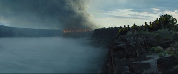 Movie still from “Only the Brave” (2017), directed by Joseph Kosinski – Two people are sitting on the edge of a cliff overlooking a fire; Extreme Wide shot, Low angle