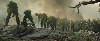 Movie still from “Only the Brave” (2017), directed by Joseph Kosinski – A group of men in yellow shirts and hats working on a forest fire; Wide shot, Low angle