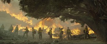 Movie still from “Only the Brave” (2017), directed by Joseph Kosinski – A group of men standing next to each other near a fire; Extreme Wide shot, Low angle