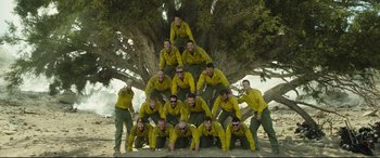 Movie still from “Only the Brave” (2017), directed by Joseph Kosinski – A group of men standing next to each other under a tree; Wide shot, Low angle