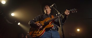Movie still from “Only the Brave” (2017), directed by Joseph Kosinski – A man in a cowboy hat is playing a guitar; Medium shot, Low angle