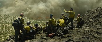 Movie still from “Only the Brave” (2017), directed by Joseph Kosinski – A group of men in yellow uniforms sitting on top of a hill; Wide shot, High angle