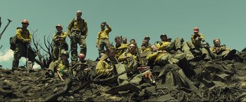 Movie still from “Only the Brave” (2017), directed by Joseph Kosinski – A group of men sitting on top of a pile of rubble; Wide shot, Low angle