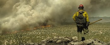 Movie still from “Only the Brave” (2017), directed by Joseph Kosinski – A man standing on top of a hill in front of a forest fire; Wide shot, Low angle