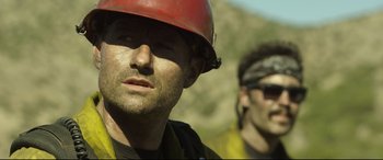 Movie still from “Only the Brave” (2017), directed by Joseph Kosinski – A person wearing a hard hat; Close Up shot, Over the shoulder angle