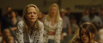 Movie still from “Only the Brave” (2017), directed by Joseph Kosinski – A woman is sitting in front of a group of people; Medium shot, Over the shoulder angle