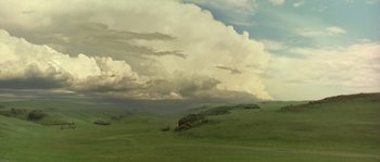 Movie still from “Open Range” (2003), directed by Kevin Costner – A large cloud filled sky over a green field; Extreme Wide shot, Low angle