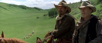 Movie still from “Open Range” (2003), directed by Kevin Costner – A man wearing a cowboy hat and holding a lasso on a horse; Medium shot, Over the shoulder angle
