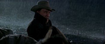 Movie still from “Open Range” (2003), directed by Kevin Costner – A man wearing a cowboy hat while standing in the rain; Close Up shot, Over the shoulder angle