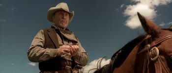 Movie still from “Open Range” (2003), directed by Kevin Costner – A man in a cowboy hat standing on a horse; Close Up shot, Low angle