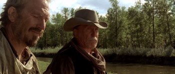 Movie still from “Open Range” (2003), directed by Kevin Costner – An older man wearing a cowboy hat near a body of water; Close Up shot, Low angle