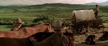 Movie still from “Open Range” (2003), directed by Kevin Costner – A man in a cowboy hat riding on a horse in a field; Wide shot, Over the shoulder angle
