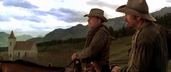 Movie still from “Open Range” (2003), directed by Kevin Costner – An older man wearing a cowboy hat sitting on top of a horse; Medium shot, Low angle