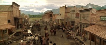 Movie still from “Open Range” (2003), directed by Kevin Costner – A group of people riding horses on a dirt road; Extreme Wide shot, High angle
