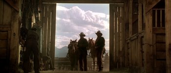 Movie still from “Open Range” (2003), directed by Kevin Costner – Two men standing next to two horses in a corral; Wide shot, Low angle