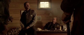 Movie still from “Open Range” (2003), directed by Kevin Costner – Two men sitting at a table in front of a window; Medium shot, Low angle
