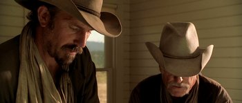 Movie still from “Open Range” (2003), directed by Kevin Costner – Two men wearing cowboy hats in front of a window; Close Up shot, Over the shoulder angle
