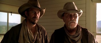 Movie still from “Open Range” (2003), directed by Kevin Costner – Two men in cowboy hats standing next to each other; Close Up shot, Low angle