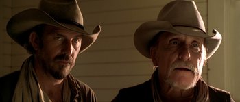 Movie still from “Open Range” (2003), directed by Kevin Costner – Two men wearing hats and a brown jacket; Close Up shot, Low angle