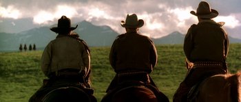 Movie still from “Open Range” (2003), directed by Kevin Costner – Two men on horses in a field with mountains in the background; Medium shot, Low angle