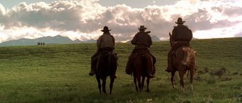 Movie still from “Open Range” (2003), directed by Kevin Costner – A group of people riding horses in a field; Wide shot, Low angle