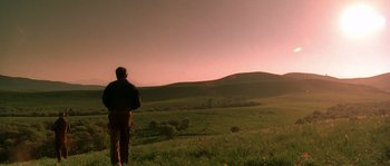 Movie still from “Open Range” (2003), directed by Kevin Costner – A man standing in a field looking out at the sky; Extreme Wide shot, Low angle