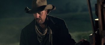Movie still from “Open Range” (2003), directed by Kevin Costner – A man wearing a cowboy hat and a black coat; Medium shot, Low angle