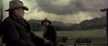 Movie still from “Open Range” (2003), directed by Kevin Costner – A man sitting on top of a horse in the middle of a field; Medium shot, Low angle