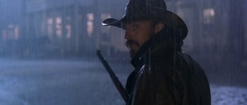 Movie still from “Open Range” (2003), directed by Kevin Costner – A man with a hat and a gun looking out of a window; Close Up shot, Low angle