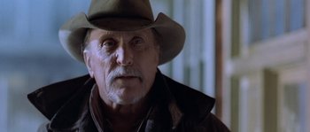 Movie still from “Open Range” (2003), directed by Kevin Costner – An older man wearing a cowboy hat and a jacket; Close Up shot, Low angle