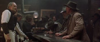 Movie still from “Open Range” (2003), directed by Kevin Costner – A group of people sitting at a bar; Wide shot, Low angle