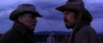Movie still from “Open Range” (2003), directed by Kevin Costner – Two men wearing hats looking into each other's eyes; Close Up shot, Over the shoulder angle