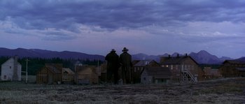 Movie still from “Open Range” (2003), directed by Kevin Costner – Two men standing on a hill looking over a town; Extreme Wide shot, Low angle