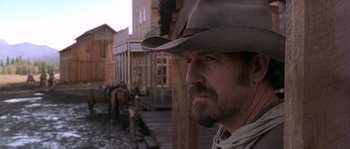 Movie still from “Open Range” (2003), directed by Kevin Costner – A man with a beard and a cowboy hat; Close Up shot, Low angle