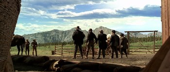 Movie still from “Open Range” (2003), directed by Kevin Costner – A group of men standing on top of a dirt field; Wide shot, Low angle
