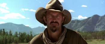 Movie still from “Open Range” (2003), directed by Kevin Costner – A man wearing a cowboy hat with mountains in the background; Close Up shot, Low angle