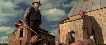 Movie still from “Open Range” (2003), directed by Kevin Costner – An old man standing in front of a group of people; Medium shot, Low angle