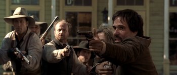 Movie still from “Open Range” (2003), directed by Kevin Costner – A group of people holding guns in front of a building; Close Up shot, Over the shoulder angle