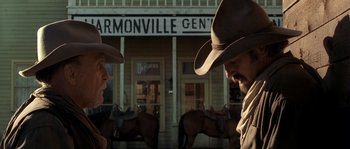 Movie still from “Open Range” (2003), directed by Kevin Costner – Two men in cowboy hats standing in front of a building; Medium shot, Low angle