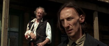 Movie still from “Open Range” (2003), directed by Kevin Costner – Two men dressed in old time clothing , one of which is holding an umbrella; Close Up shot, Low angle