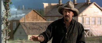 Movie still from “Open Range” (2003), directed by Kevin Costner – A man wearing a cowboy hat is standing outside; Close Up shot, Over the shoulder angle
