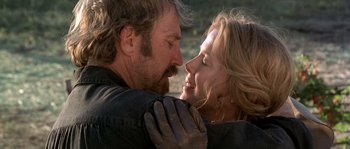 Movie still from “Open Range” (2003), directed by Kevin Costner – A man and a woman embracing each other in a field; Close Up shot, Low angle